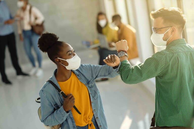 students wearing masks fist bumping